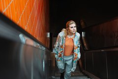 Frau auf Rolltreppe mit auffällig gemustertem Mantel