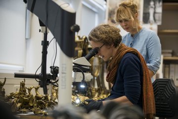eine Frau untersucht Details mit dem Mikroskop