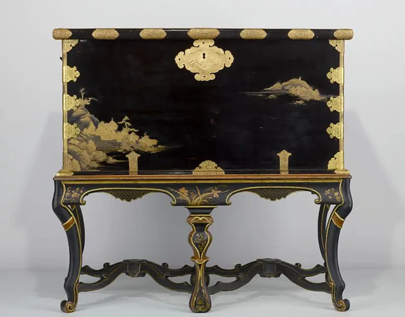 Truhe mit langen Tischbeinen und goldenen Zeichnungen