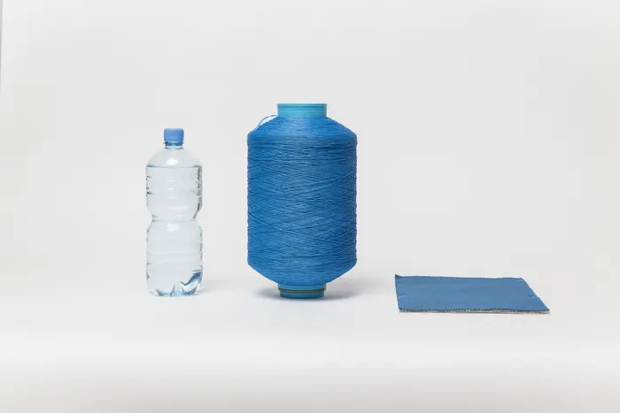 Wasserflasche, eine Rolle Garn und ein Stück Stoff nebeneinander