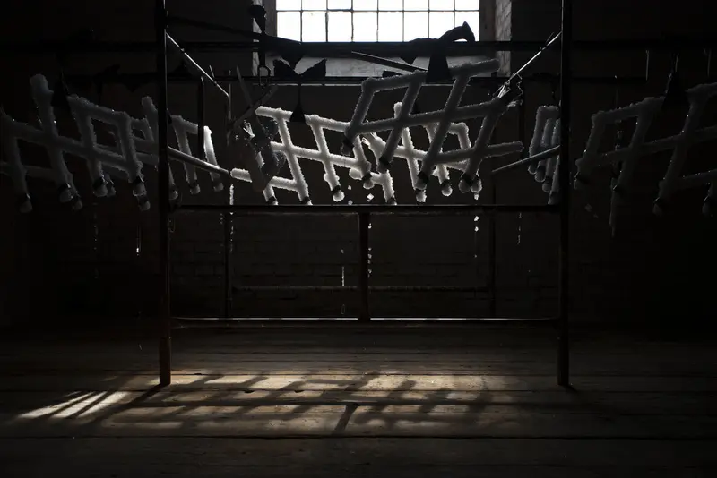 Eckiges Metallgerüst in einem dunklen Raum vor einem hellen Fenster