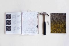 Buch mit Häkelanleitungen, daneben Skizze, Hammer, Nägel und eine Art besticktes Textil