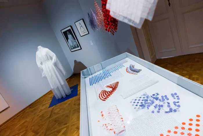 Ausstellungsansicht von einer Vitrine mit Stoffen und eines weißen Kleides