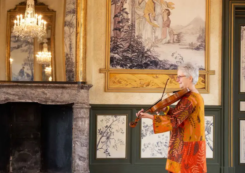 Frau, die Geige in einem prunkvollen Festsaal spielt