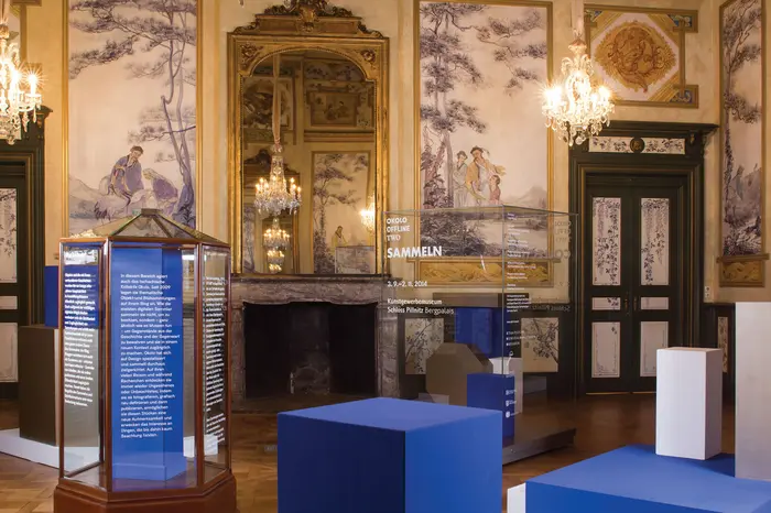 leere Sockeln und beschriftete, leere Vitrinen in Raum mit asiatischen Wandmalereien