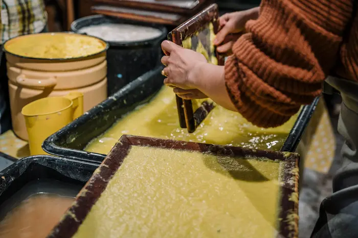 gelbe Flüssigkeit in einem Rahmen zum Papierschöpfen