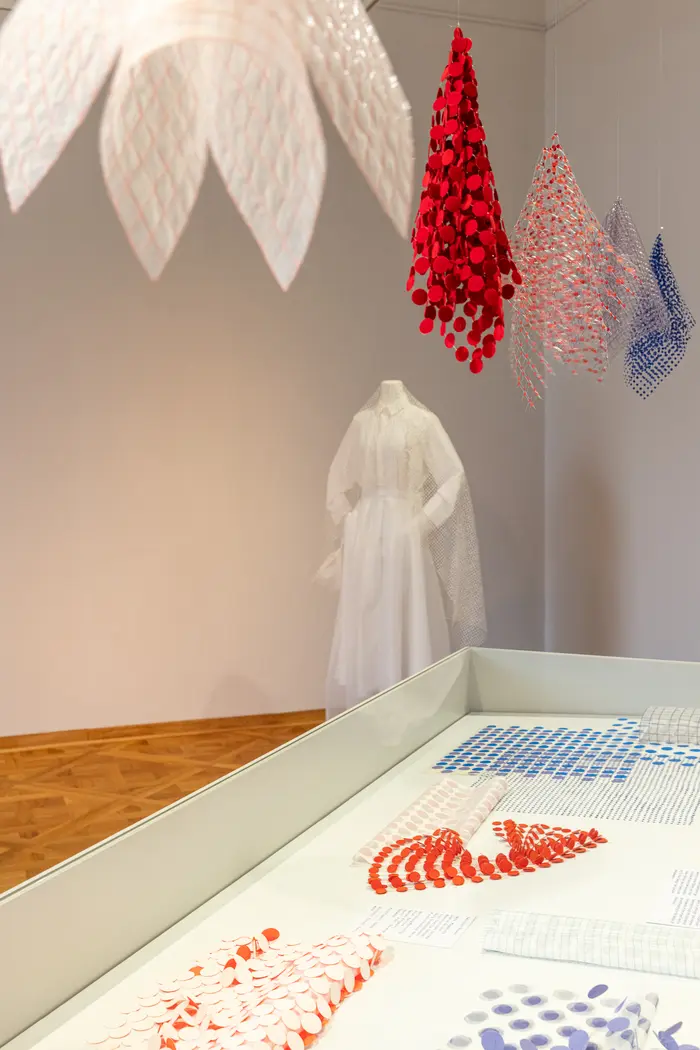 Ausstellungsansicht verschiedener Stoffproben und einem weißen Kleid mit Schleier 