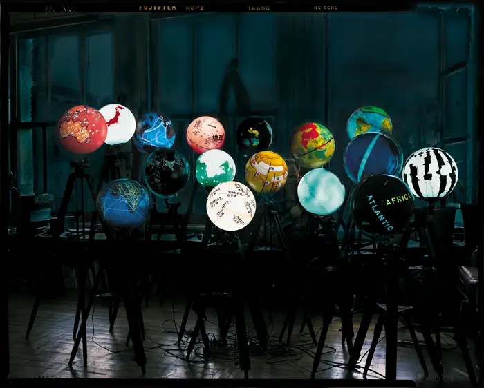 Bunt leuchtende Globen in einem dunklen Raum mit unterschiedlichen Darstellungen der Welt 