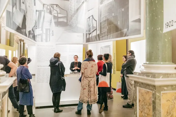 Frauen hören einer Rednerin in einer Ausstellung zu