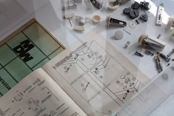 Bauanleitungen und verschiedene Bauteile in einer Vitrine