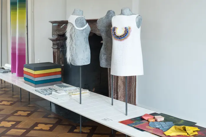 drei teils bekleidete Kleiderbüsten, daneben Stoffe