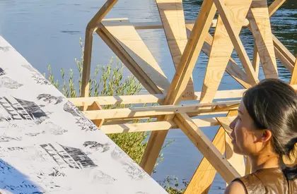 Papierpresse aus Holz im Hintergrund, davor Personen
