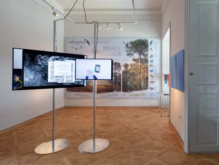 Ausstellungsansicht mit vielen Monitoren und einer Informationsgrafik 