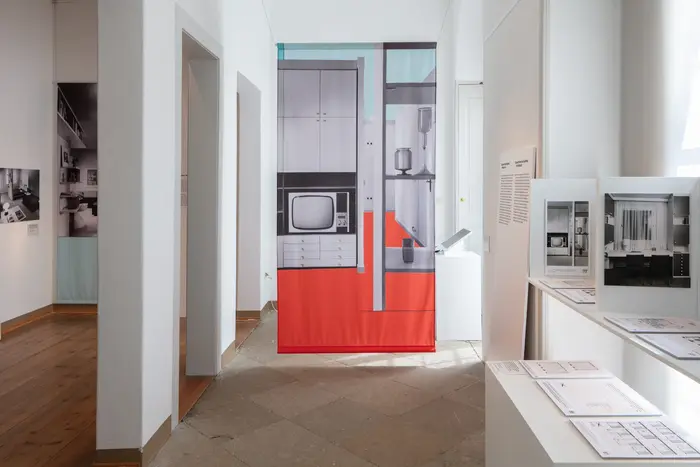 Ausstellungsansicht mit verschiedenen Fotografien von Inneneinrichtungen und Informationstafeln