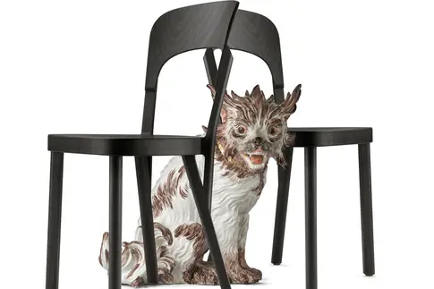 Porzellanhund sitzt zwischen zwei Stühlen