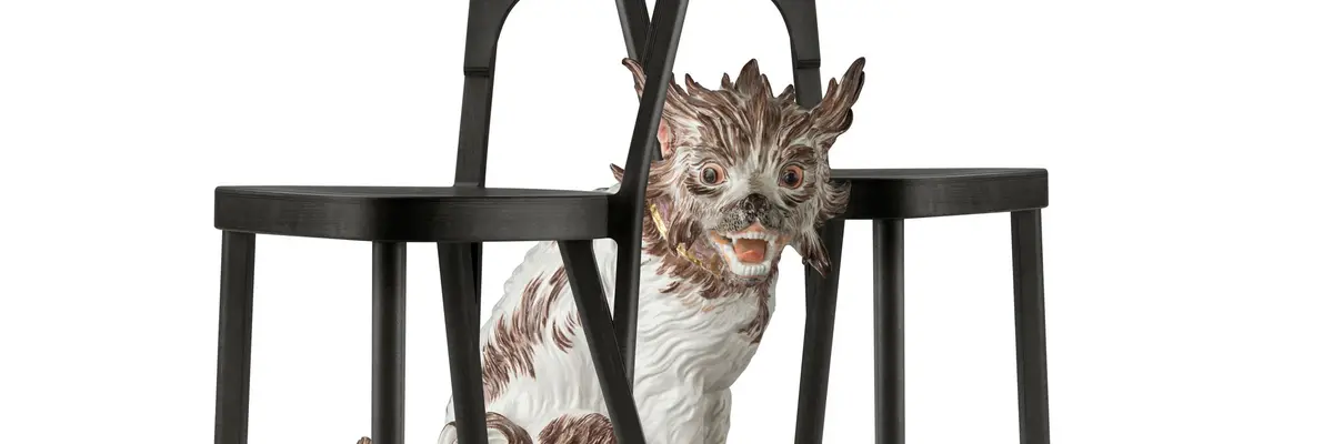 Porzellanhund sitzt zwischen zwei Stühlen