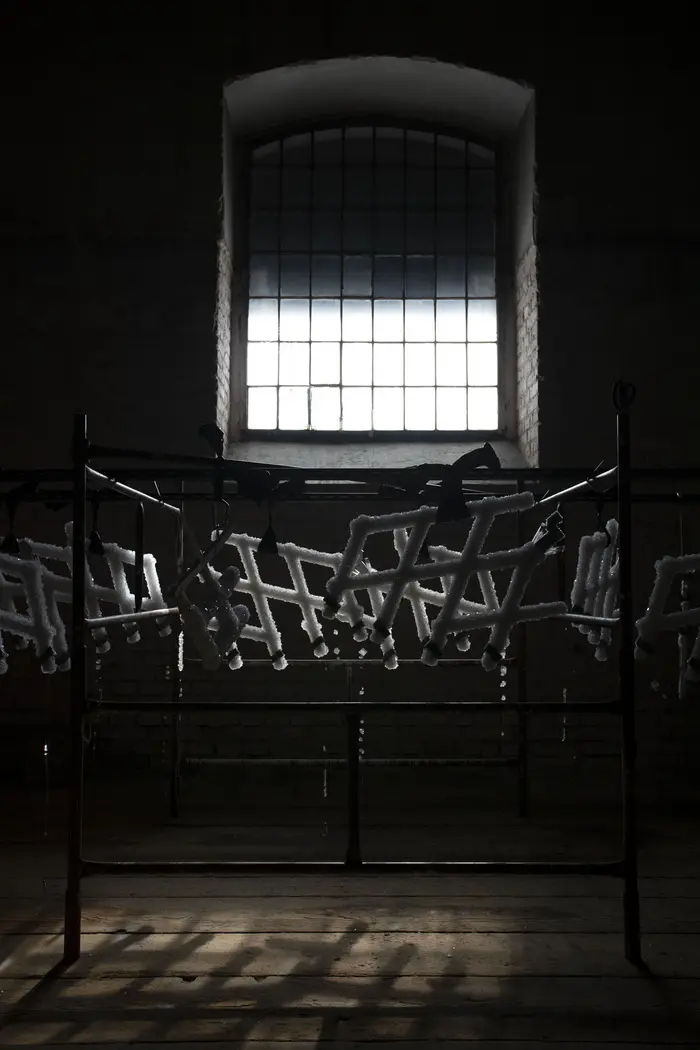 Metallgerüst in einem dunklen Raum vor einem hellen Fenster