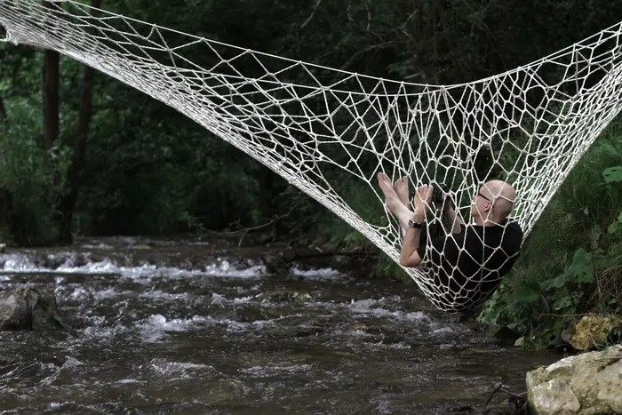 Mann liegt in einem Netz über einem Fluss